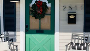 Una puerta verde con una corona de laurel, un buzón y el número 2511 en la pared.
