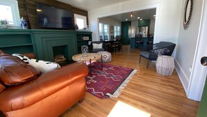 Una sala de estar con un sofá de cuero, chimenea, televisor y un comedor con sillas y mesa.