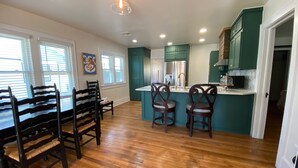 Una cocina amplia con suelo de madera, armarios color turquesa y una isla central con taburetes.