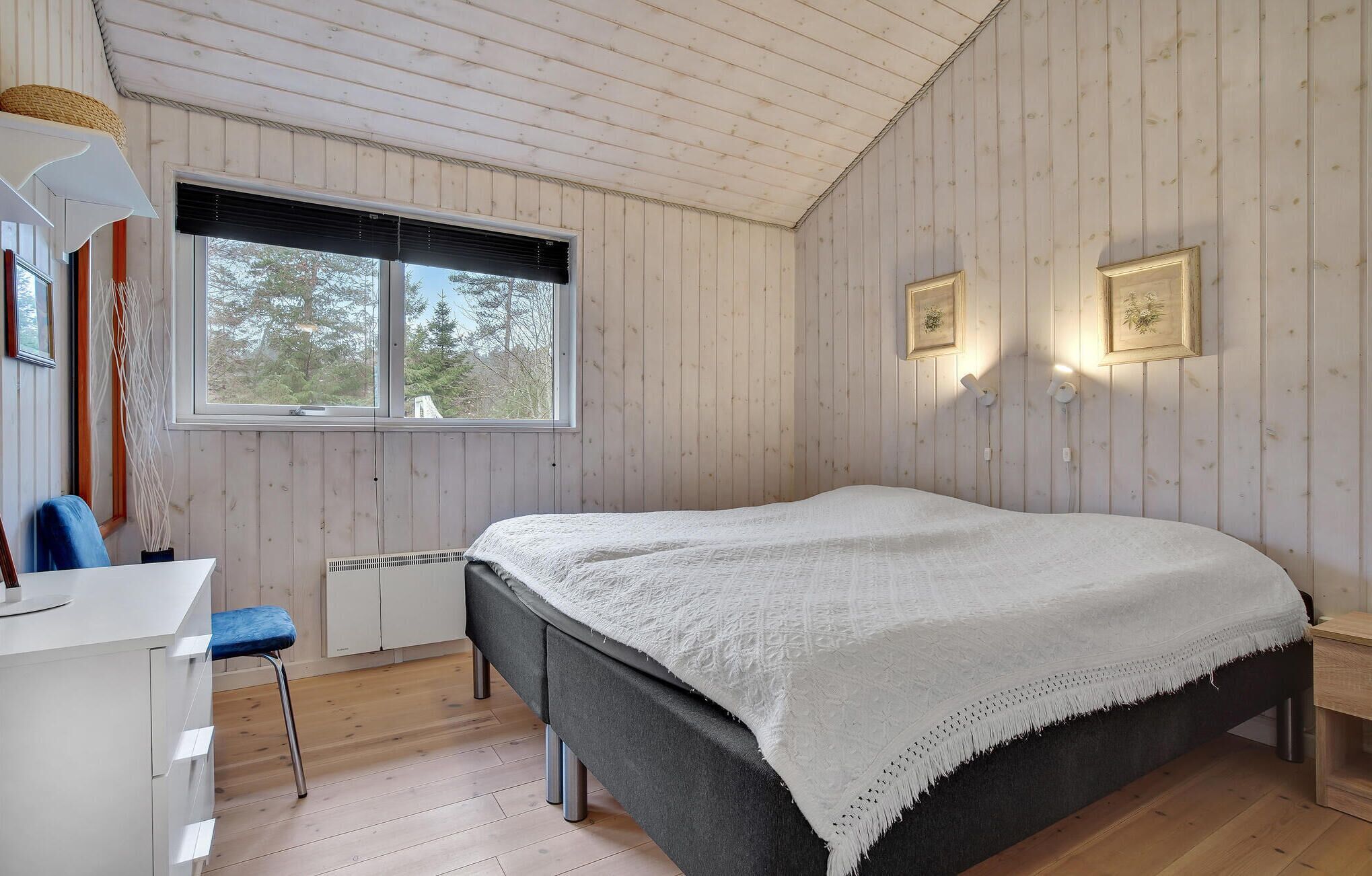 A bedroom with a bed, a desk, and a chair.