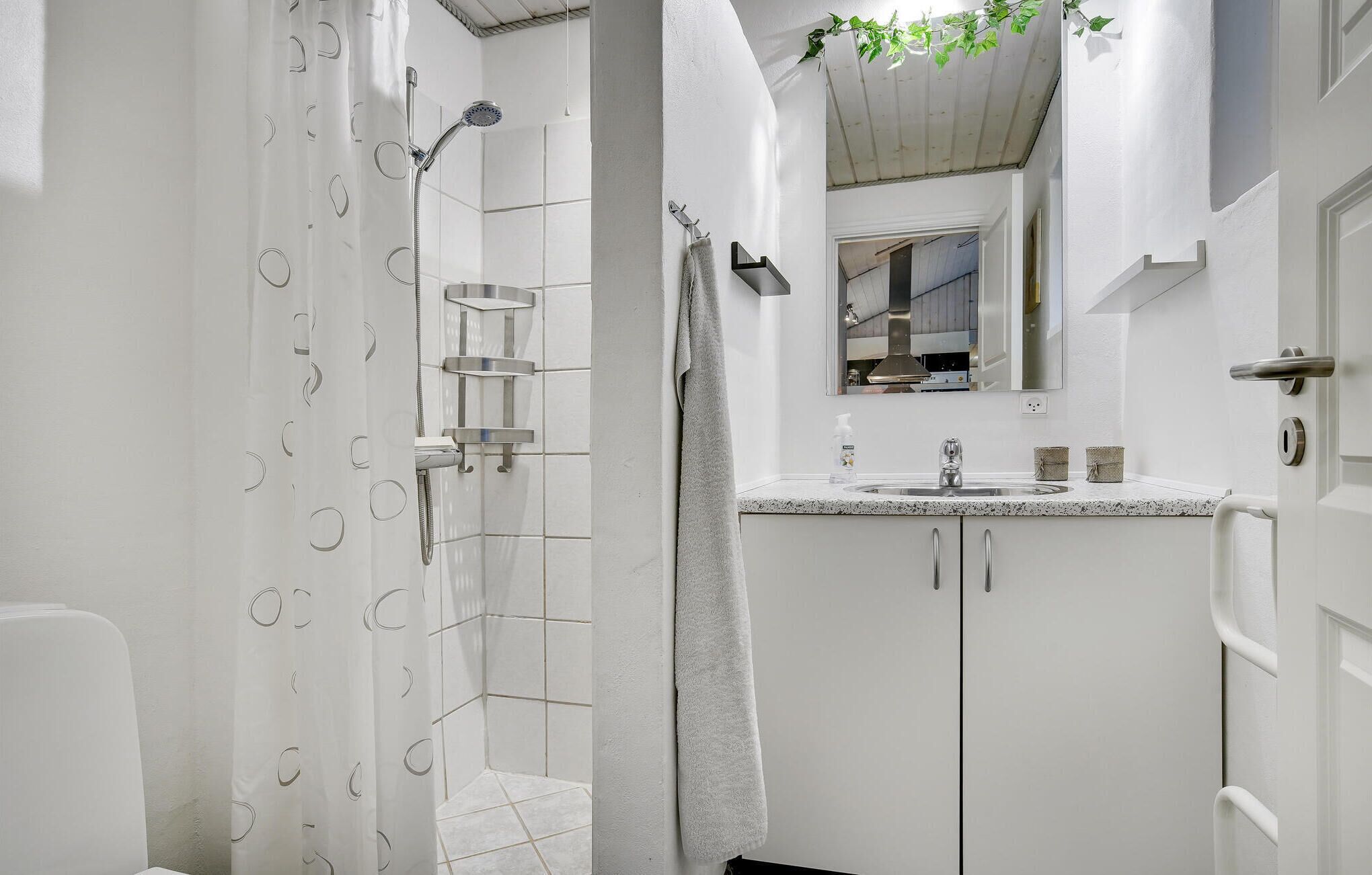 A bathroom with a shower, a sink, and a mirror.