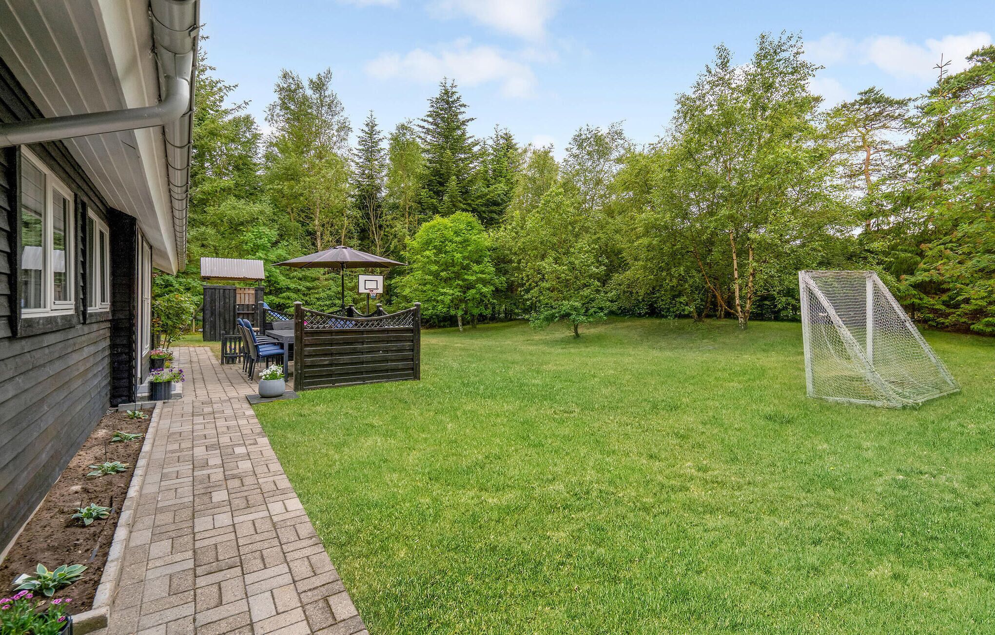 A backyard with a patio, a basketball hoop, and a soccer goal.