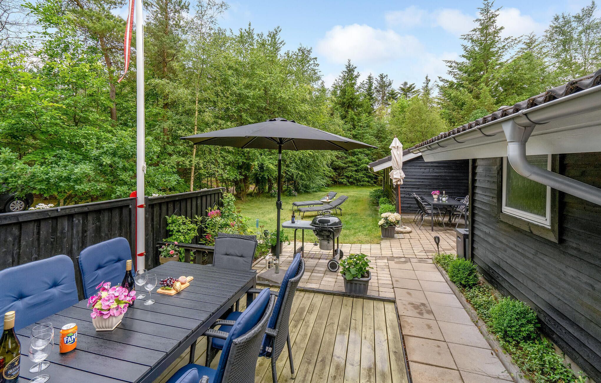 Une terrasse avec une table dressée pour les repas, des sièges d’extérieur et un barbecue.