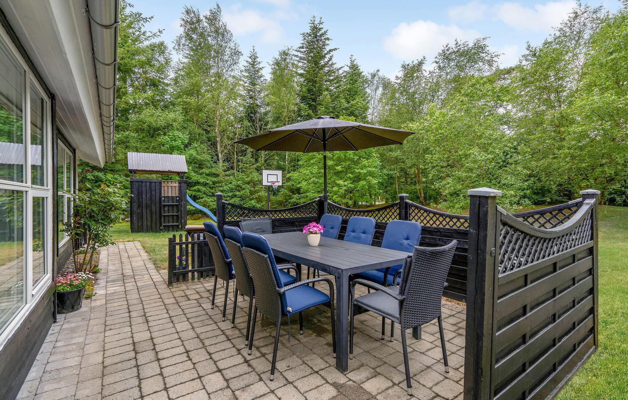 An outdoor patio with a table and chairs, a basketball hoop, and a wooden play structure.