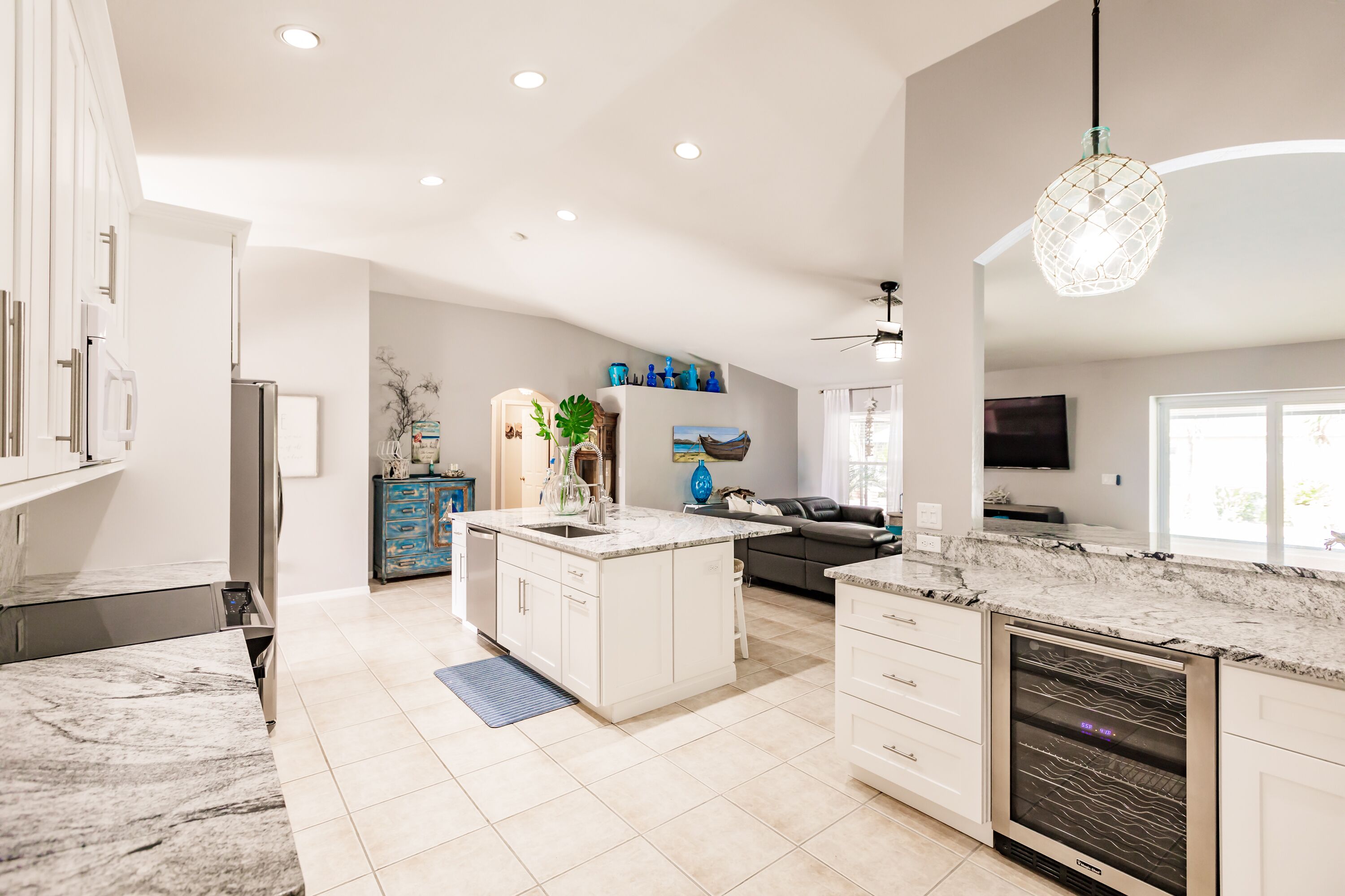 A modern kitchen with white cabinetry, a marble countertop, and a built-in oven.