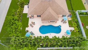 Une grande maison avec une piscine, du mobilier de jardin et une pelouse bien entretenue.