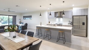 Una cocina moderna con una isla central, taburetes de bar y un refrigerador de acero inoxidable.