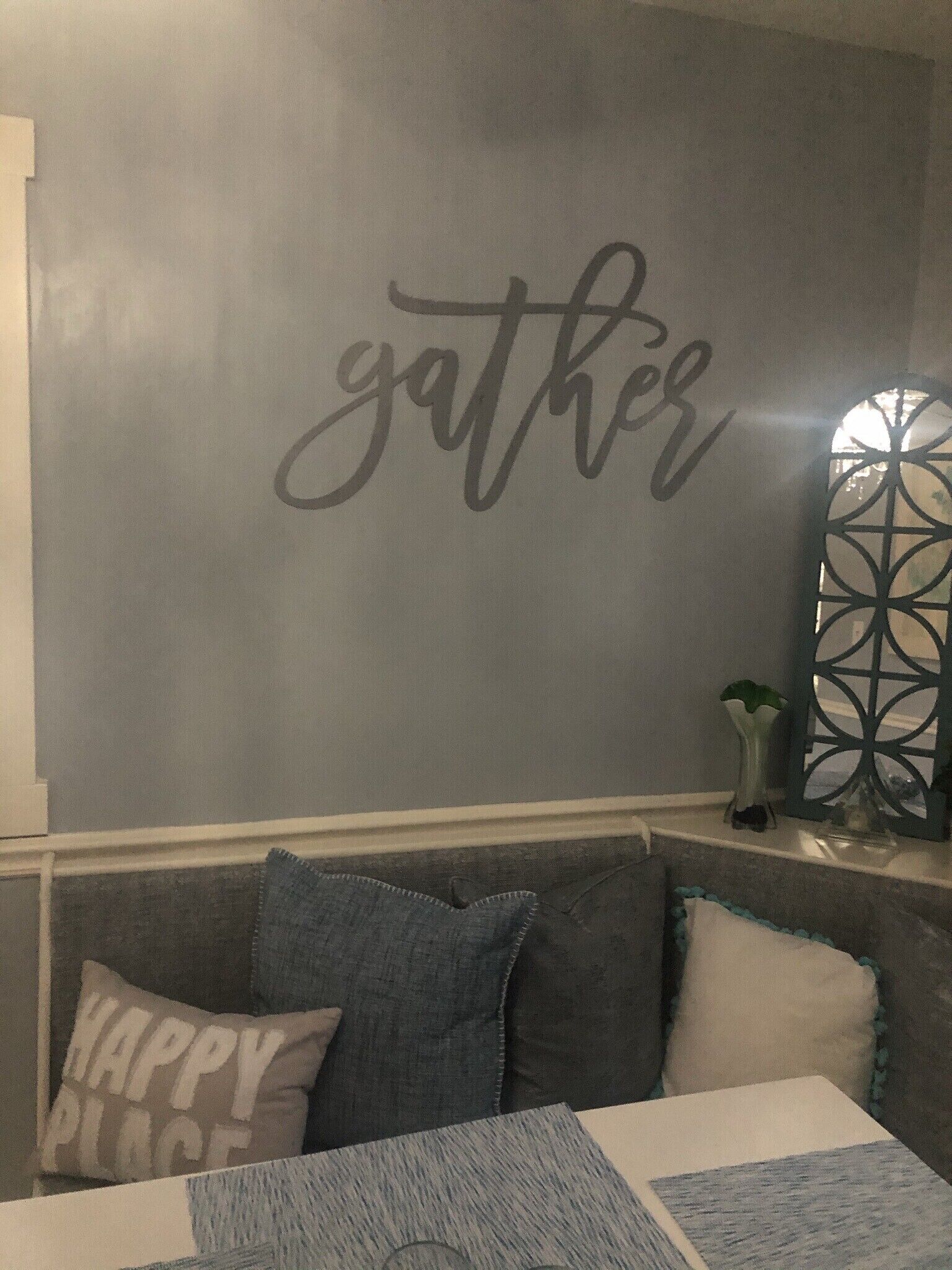 A room with a wall that says "gather" and a couch with a "happy place" pillow.