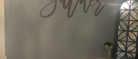 A room with a wall that says "gather" and a couch with a "happy place" pillow.