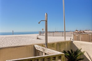 Vista de playa con cerca de madera, muro de hormigón y estructura metálica.