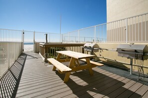 Une terrasse en bois avec une table de pique-nique et un barbecue.