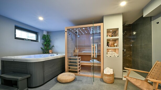 A modern bathroom with a large hot tub, a glass-enclosed shower area, and a wooden chair. - Gorgeous home in Popovaca with sauna (Popovaca)
