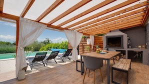 An outdoor patio with a wooden pergola, a pool, and a barbecue area. - Gorgeous home in Popovaca with sauna (Popovaca)