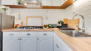 A modern kitchen with white cabinets, a stainless steel sink, and a wooden countertop. - Gorgeous home in Popovaca with sauna (Popovaca)
