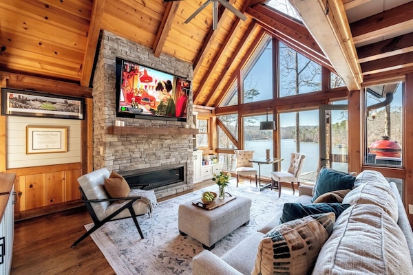 Soaring A-frame great room with stone fireplace, smart TV & unobstructed Lake Lanier views — the cozy heart of this Hygge House lakefront retreat near Gainesville, GA for couples, families & groups of 8.