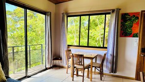 A room with a bed, a table with chairs, and large windows with curtains. - Private Attached 1BR in Monteverde - Gulf Views - Sleeps 3 (Monteverde)