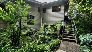 A house with a wooden staircase leading to a front door, surrounded by lush greenery and a variety of plants. - Private Attached 1BR in Monteverde - Gulf Views - Sleeps 3 (Monteverde)