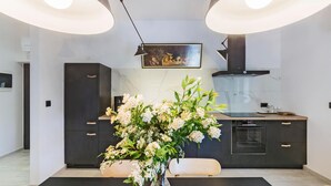 Een moderne keuken met donkere kastjes, een marmeren achterwand en een centraal eiland met een bloemenvaas.