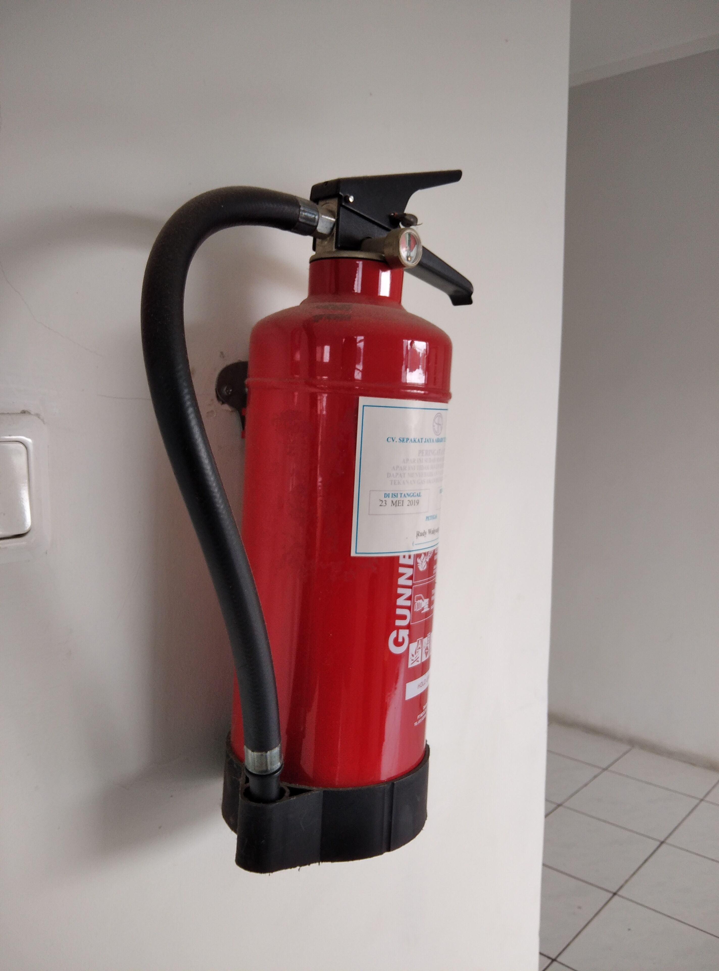 A red fire extinguisher mounted on a white wall.