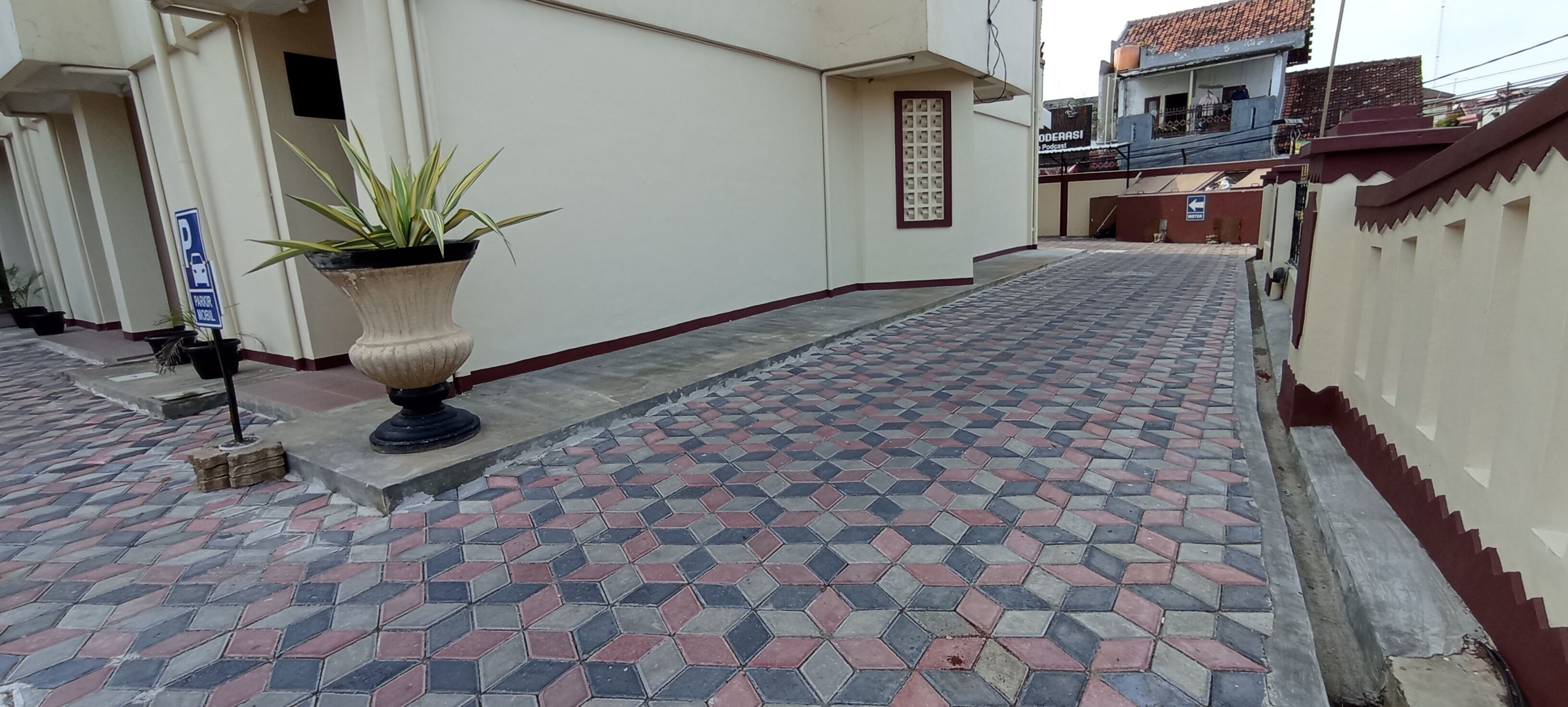 Ein gepflasterter Weg mit Parkschild, Blumentopf und einem Gebäude mit Ziegeldach.