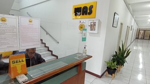 A reception desk with informational posters, a 'No Smoking' sign, a 'Stay' sign, and a 'Bell' sign. - Wisma Anton Soedjarwo (Jakarta)