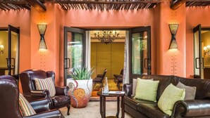 A lobby with leather sofas, a coffee table, and a large potted plant. - Avani Victoria Falls Resort (Livingstone)