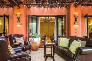 A lobby with leather sofas, a coffee table, and a large potted plant. - Avani Victoria Falls Resort (Livingstone)
