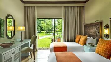 Quarto de hotel com duas camas, uma escrivaninha, uma cadeira e vista para um jardim.