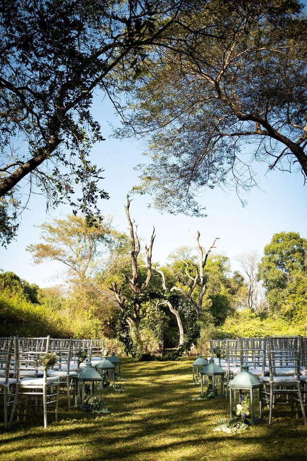 Un salón de bodas al aire libre con filas de sillas y faroles verdes.