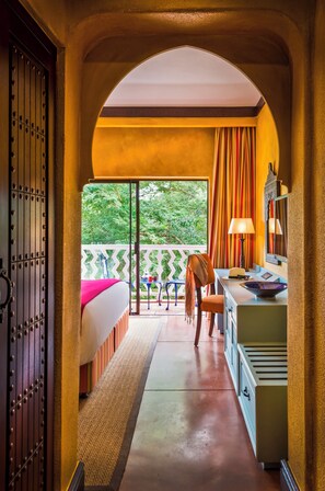 Una habitación con cama, escritorio, silla y vistas a zonas verdes.