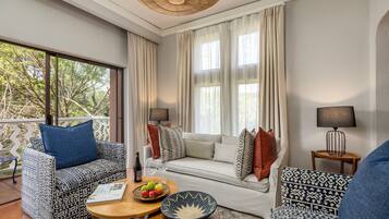 Una sala moderna con mobiliario estampado, una mesa de comedor con fruta y vistas a árboles a través de grandes ventanales.