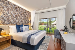 A modern hotel room with a large bed, a desk, and a view of the outdoors. - Avani Victoria Falls Resort (Livingstone)
