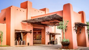 A building with a distinctive architectural style, featuring a large entrance and a covered area with a metal roof. - Avani Victoria Falls Resort (Livingstone)