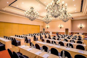 A conference room with multiple tables, chairs, and chandeliers. - Avani Victoria Falls Resort (Livingstone)