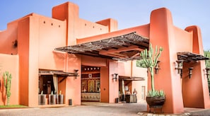 A building with a distinctive architectural style, featuring a large entrance and a covered area with a metal roof. - Avani Victoria Falls Resort (Livingstone)