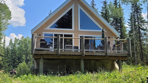 A wooden cabin with a balcony, surrounded by trees.