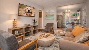 Een woonkamer met een bank, fauteuils, een salontafel, een televisie en een boekenkast.