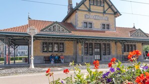 Une gare historique à la façade jaune caractéristique, agrémentée de touches de vert.