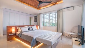 Een moderne slaapkamer met een groot bed, een inbouwkast, een plafondventilator en een televisie.