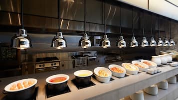 A buffet setup with various food items and a modern kitchen in the background.