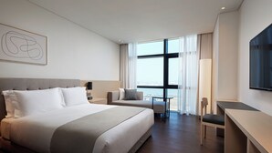 A modern hotel room with a large bed, a desk, and a view of the sea through large windows. - Shilla Stay Seobusan (Busan)