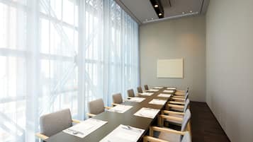 A conference room with a long table, chairs, and a large window with blinds.