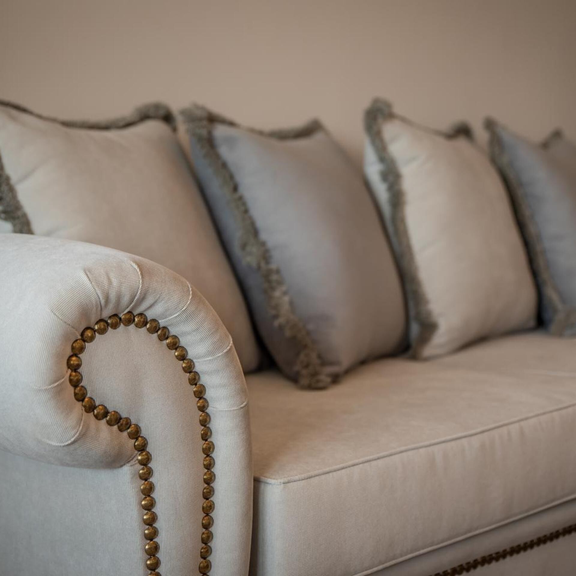 A section of a light-colored sofa with a decorative beaded trim.