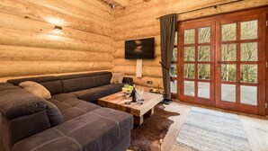 A log cabin interior with a sectional sofa, a wooden coffee table, and a TV mounted on the wall. - Gorgeous home in Brod Na Kupi with sauna (Brod Na Kupi)