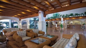 A spacious lobby with wicker furniture, a staircase, and a reception area. - Club Royal Son Bou (Alayor)
