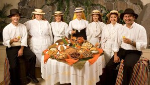 A group of people seated around a table with a variety of food items, in a room with a stone wall backdrop. - Gran Rey (Valle Gran Rey)