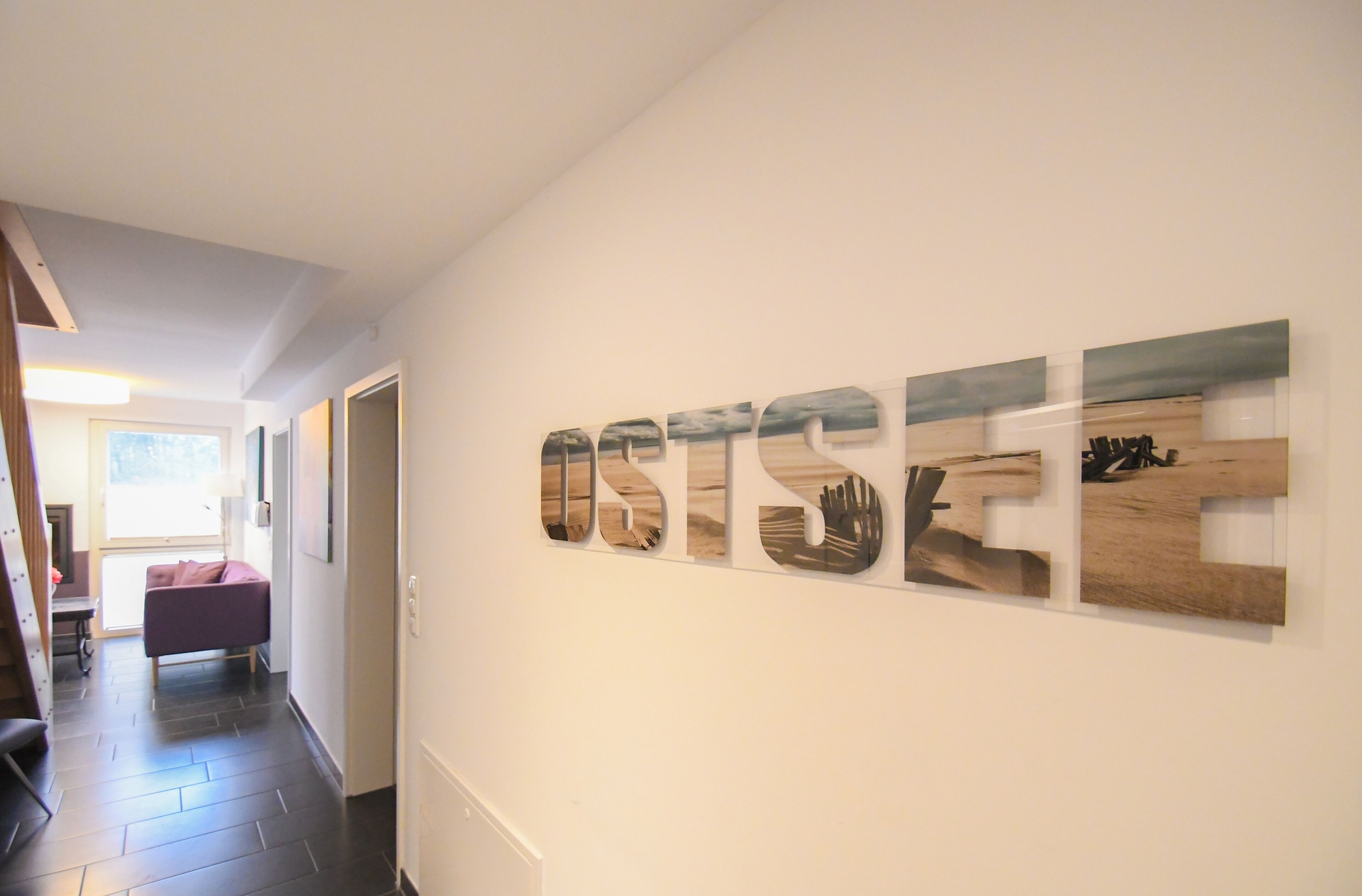 A hallway with a large wooden sign spelling "OSTSEE" on the wall.