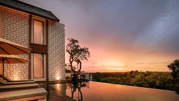 A modern building with a pool, lounge chairs, and a sunset view. - One Degree Sunset Hill Leisure (Pecatu)