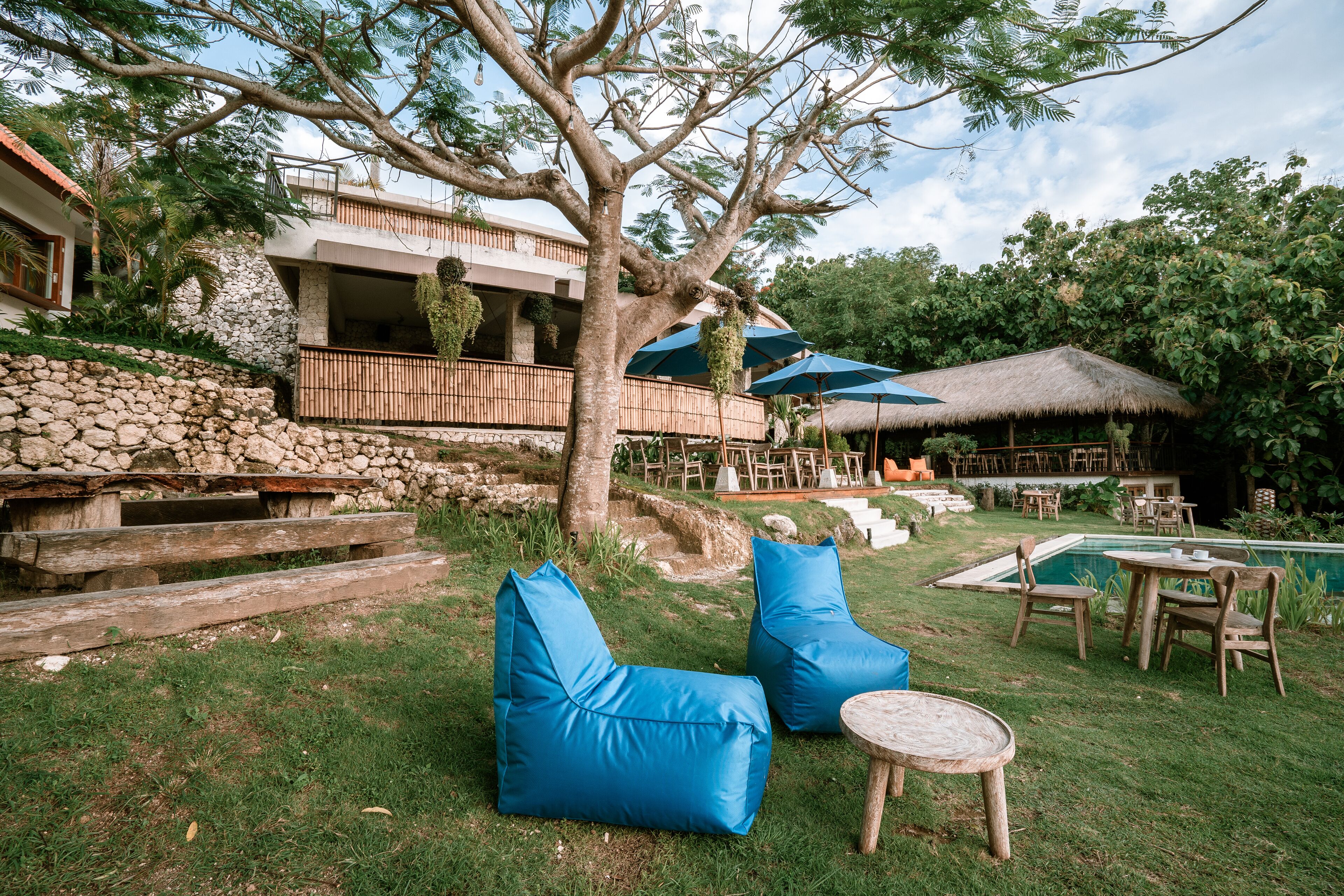 A poolside area with outdoor seating, a stone wall, and a building with a balcony.