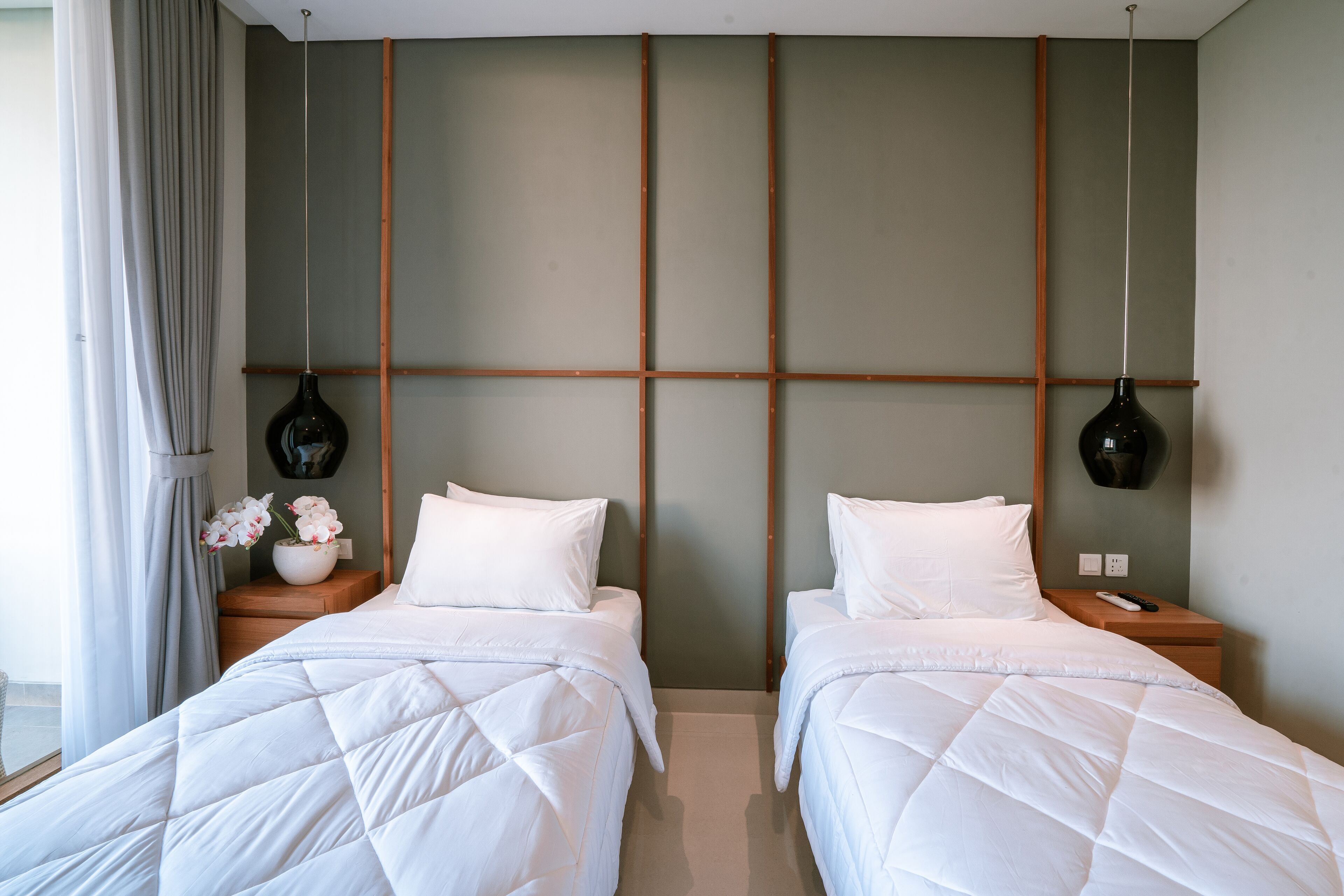 Una habitación de hotel con dos camas, un cabecero de madera y un florero sobre la mesita de noche.